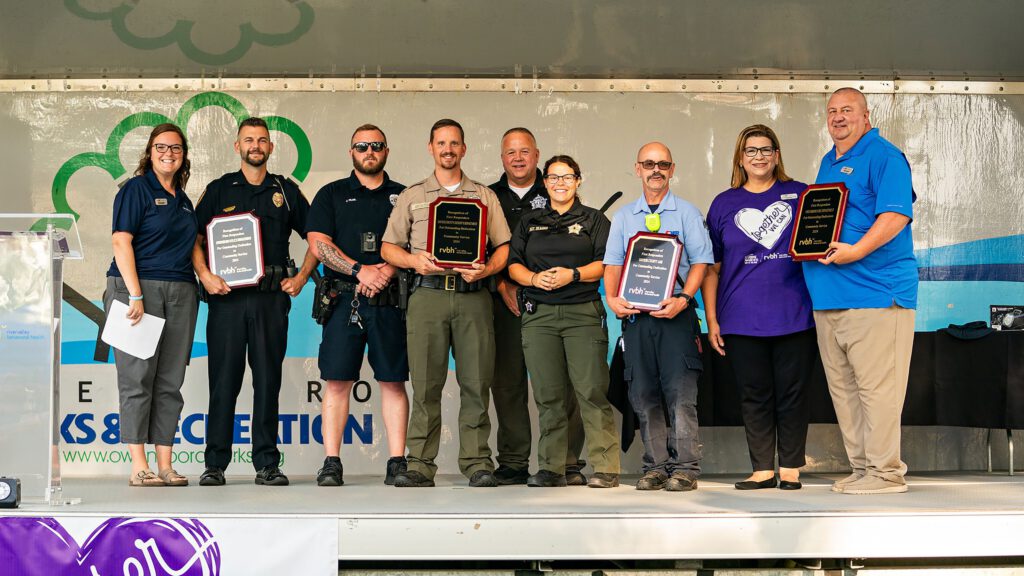 Group on stage with first responders holding plaques during an awards presentation.
