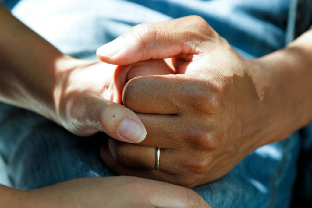 Close-up of two people holding hands in a supportive gesture.