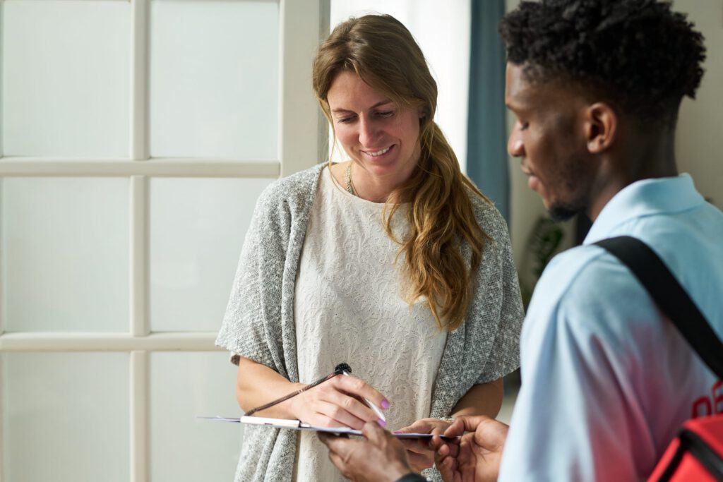 Intake coordinator warmly welcoming a new client and explaining the admissions process at a treatment center