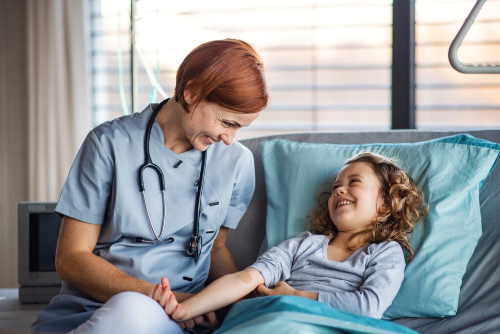 Nurse smiling with a child resting in a hospital bed