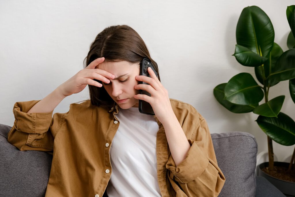 Stressed woman talking on the phone while sitting on a couch