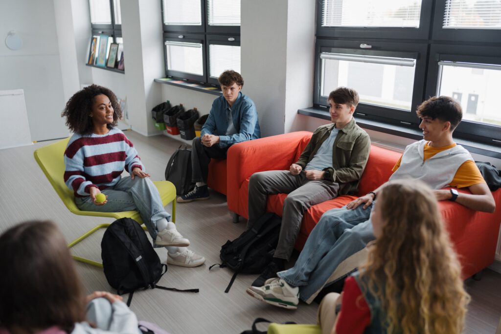 Teenagers seated in a circle during a group discussion in a bright room.